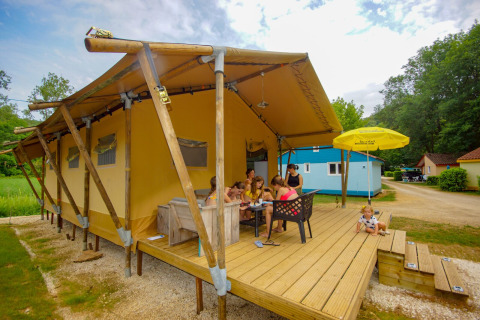 Familia disfruta de una comida al aire libre frente a una tienda safari Lodgetent Bordeaux en La Draille, Francia.