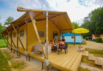 Familie nyder udendørs måltid foran en safari telt Lodgetent Bordeaux på La Draille campingplads, Frankrig.