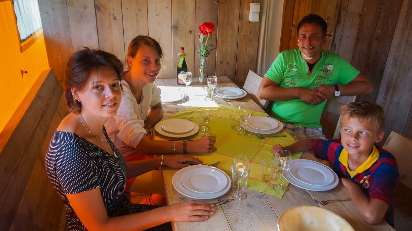 Gezin rond tafel in safaritent Lodgetent Bordeaux bij La Draille in Frankrijk, klaar om te gaan eten.