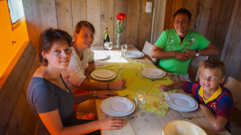Familie sitzt am Tisch im Safarizelt Lodgetent Bordeaux bei La Draille in Frankreich und wartet aufs Essen.
