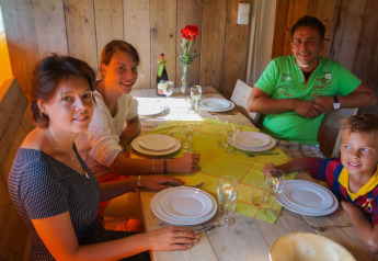 Familie sidder omkring et bord i en safari telt Lodgetent Bordeaux på La Draille, Frankrig, klar til middag.