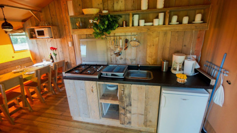 Keuken in een safaritent Lodgetent Bordeaux bij La Draille in Frankrijk, met houten panelen en eettafel.
