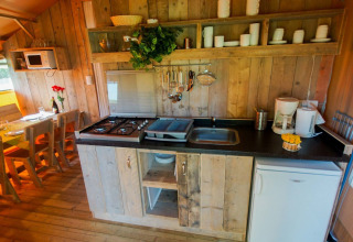 Zona de cocina en una tienda safari Lodgetent Bordeaux en La Draille, Francia, con paneles de madera y mesa.
