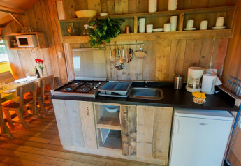 Zona de cocina en una tienda safari Lodgetent Bordeaux en La Draille, Francia, con paneles de madera y mesa.