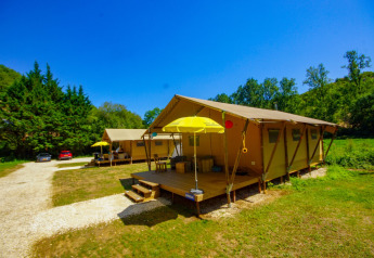 Safari tent Lodgetent Bordeaux at La Draille, France, with porch, yellow umbrella, and green natural setting.