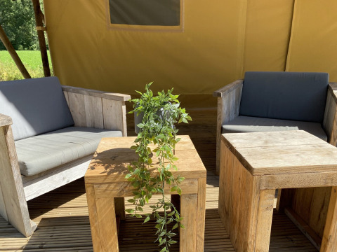 Zona de estar al aire libre con muebles de madera y planta verde en Lodgetent Bordeaux, La Draille, Francia.
