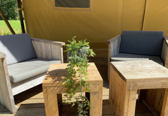 Coin salon extérieur avec meubles en bois et plante verte au Lodgetent Bordeaux, La Draille, en France.