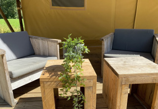 Zona de estar al aire libre con muebles de madera y planta verde en Lodgetent Bordeaux, La Draille, Francia.