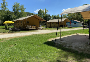 Safari-teltene Lodgetent Bordeaux på La Draille i Frankrig, placeret i det grønne med siddeområder udenfor.