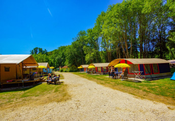 Safari tent Lodgetent Bordeaux at La Draille, France, with people relaxing outside on a sunny day by the trees.