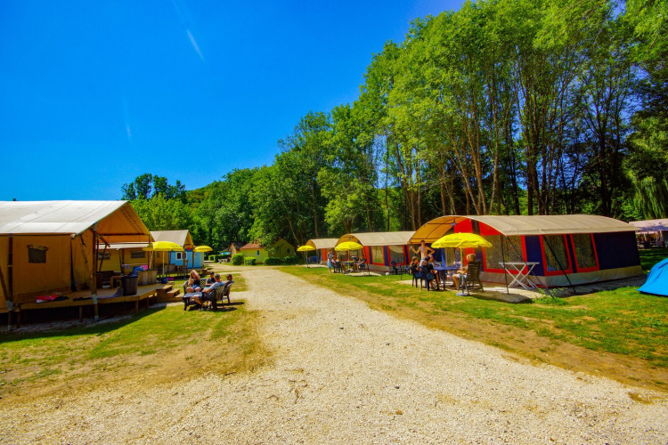 Safari tent Lodgetent Bordeaux at La Draille, France, with people relaxing outside on a sunny day by the trees.