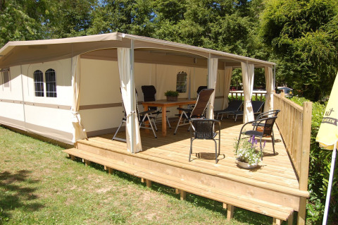Tienda safari Glampingtent Cahors en La Draille, Francia, con terraza de madera cubierta, sillas y mesa al aire libre.