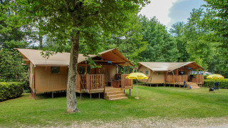 Tiendas safari en Lodgetent Brive, La Draille, Francia, rodeadas de árboles verdes y un entorno tranquilo.