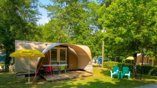 Safaritent Le Petit Chateau aan La Draille in Frankrijk, met terras, stoelen en groene, bosrijke omgeving.