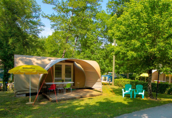 Tienda safari Le Petit Chateau en La Draille, Francia, con terraza de madera y sillas en un entorno verde.