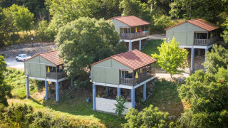 Vier verhoogde chalets met rode daken tussen het groen bij Chalet Belvedere, La Draille in Frankrijk.