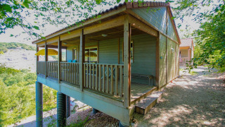 Chalet Belvedere Deluxe bij La Draille in Frankrijk, een verhoogde houten lodge omgeven door groen.