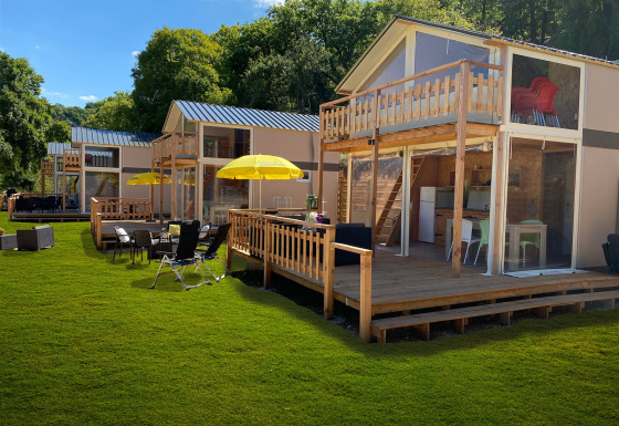 Tienda safari de lujo Belle Vue en La Draille, Francia, con terraza de madera y zona de descanso exterior.