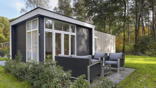 Casa pequeña moderna con terraza y muebles de exterior en Bospark Markelo, Países Bajos, rodeada de bosque.