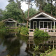 To små sorte hytter ved en dam omgivet af træer i Lodge Meerkoet, Bospark Markelo, Holland.