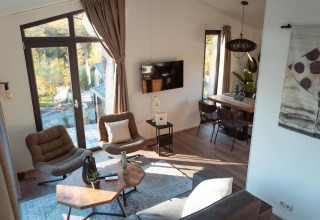 Interior moderno y luminoso de lodge con grandes ventanales, sillones cómodos y mesa de madera.