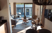 Sala de estar moderna y acogedora de lodge, con grandes ventanas, cómodos asientos y vista a la terraza.