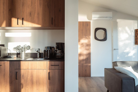 Foto interior soleada de una moderna cocina de lodge con gabinetes de madera y una acogedora sala de estar.