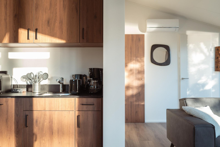 Sunny interior photo of a modern lodge kitchen with wood cabinets, appliances, and a cozy living area.