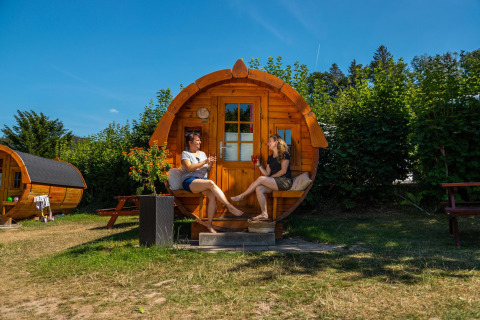Zwei Personen entspannen vor einer Traktorcabin am Biggesee in Deutschland bei sonnigem Wetter.