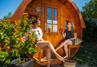 To kvinder nyder drikkevarer foran en træhytte kaldet Tractor cabin ved Biggesee, Tyskland.