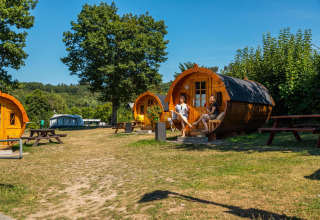 Due persone si rilassano davanti alle baite a forma di trattore al lodge Biggesee in Germania in una giornata soleggiata.