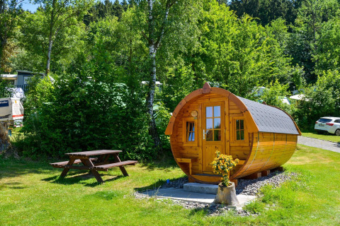 Traktorhütte am Biggesee in Deutschland. Fassförmige Holzhütte mit Picknicktisch im Grünen.