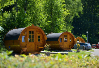 Tractor cabin al Biggesee in Germania, circondate da alberi verdi e auto parcheggiate vicino.