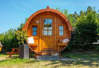 Cabaña redonda de madera Tractor Cabin en Biggesee, Alemania, rodeada de vegetación y cielo azul claro.