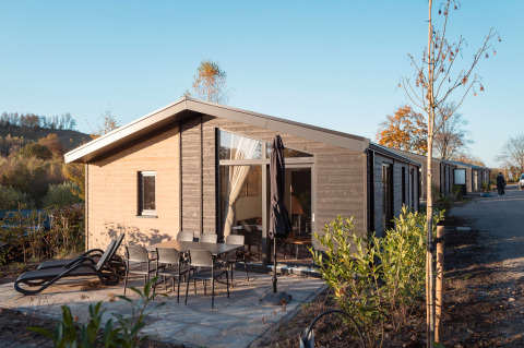 Buitenfoto van Hackfort MIVA-lodge met terras, tuinstoelen en ligzetels op een heldere dag.