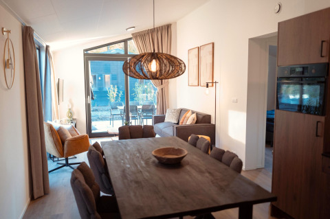 Moderne lodge Hackfort MIVA aan de Biggesee in Duitsland met eettafel, zithoek en grote ramen.