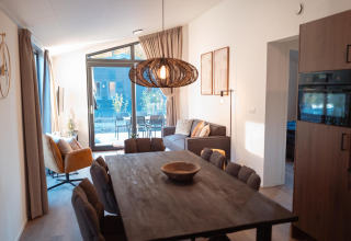 Moderna cabaña Hackfort MIVA en Biggesee, Alemania, con comedor, sofá cómodo y ventanales amplios.