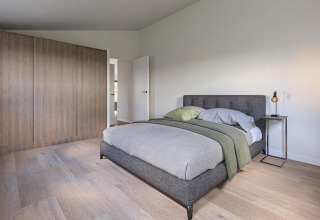 Modern bedroom at Hackfort MIVA, Biggesee, Germany, with double bed, wood floor, and minimalist décor.