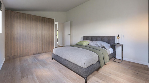 Modern bedroom at Hackfort MIVA, Biggesee, Germany, with double bed, wood floor, and minimalist décor.