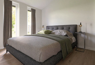 Moderne slaapkamer in een lodge met grote ramen, grijs bed, minimalistisch ingericht en houten vloer.