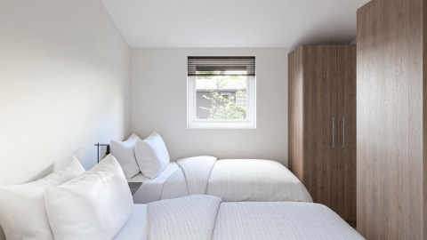 A bright lodge room with two single beds, white bedding, a window with a view, and a wooden wardrobe.