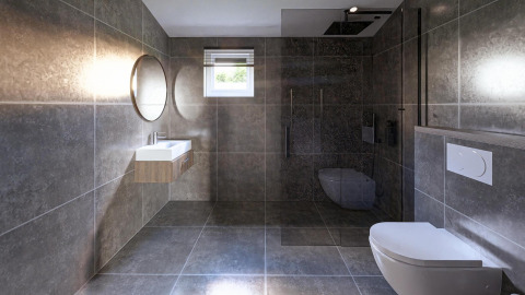 Modern bathroom at a lodge featuring gray tiles, wall-mounted toilet, walk-in shower, and round mirror.