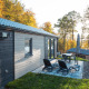 Udendørs terrasse med stole og borde ved Hackfort-lodgen, omgivet af træer i efterårsfarver.