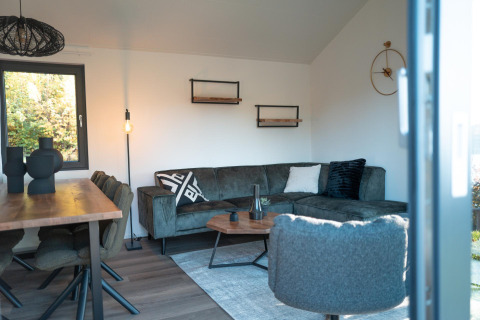 Salon moderne du lodge Hackfort au Biggesee, Allemagne, avec canapé d’angle confortable et déco élégante.