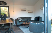 Salón moderno en la cabaña Hackfort en Biggesee, Alemania, con sofá esquinero y decoración elegante.