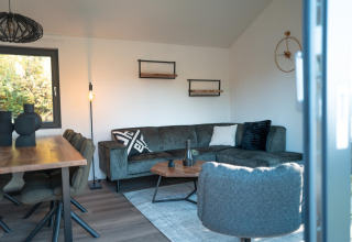Moderne stue i Hackfort-lodge ved Biggesee, Tyskland, med hjørnesofa, spisebord og elegant indretning.