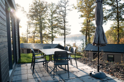 Patio with table and chairs at Hackfort Lodge overlooking lake and forest views at Biggesee, Germany.