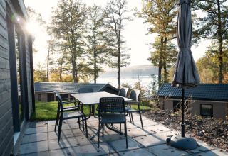 Patio with table and chairs at Hackfort Lodge overlooking lake and forest views at Biggesee, Germany.