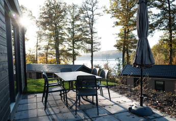 Terrasse avec table et chaises au lodge Hackfort, vue sur le lac et la forêt à Biggesee, en Allemagne.