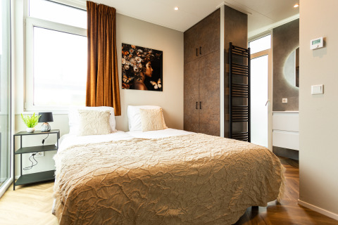 Moderne slaapkamer bij Waterhoeve Wellness (Hottub) in Park Westerkogge, Nederland, met comfortabel bed en badkamer.